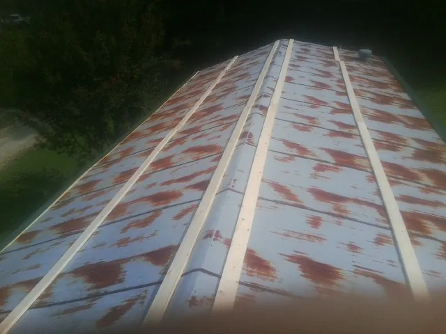 Rusted metal roof panels with new wood purlins before replacement — Storm Damage Roof Repair in Saratoga Springs by Roofing Brothers
