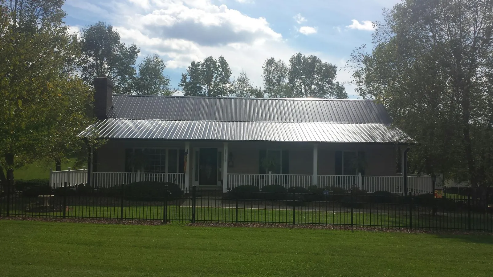 Gray metal roof on a brick ranch with a full width front porch — Gutter Guard Installation work by our crew in Saratoga Springs