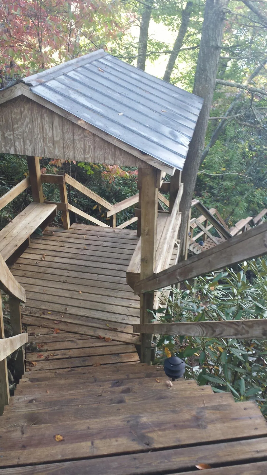Metal roofed shelter over wooden steps on a wooded walkway — Skylight Repair & Installation work by our crew in Saratoga Springs